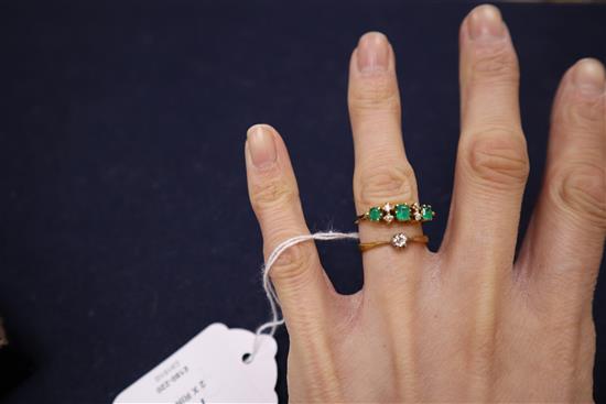 An 18ct, emerald and diamond half hoop ring and an 18ct solitaire diamond ring.